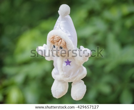 Plush white doll on a green background .
