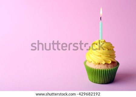 Birthday cupcake with candle on light pink background