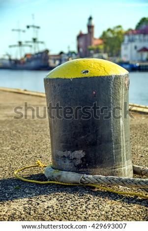 bollard in a seaport with sailing ship and lighthouse
