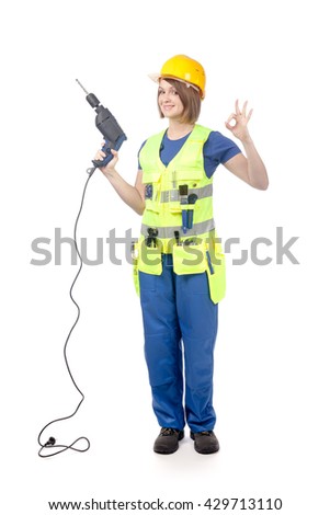smiling construction female worker in yellow hardhat and reflective vest holding a drill and showing okay sign isolated on white background. proposing service. advertisement gesture