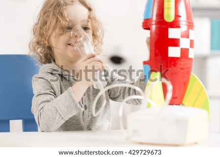 Happy child with oxygen mask playing with toy racket Royalty-Free Stock Photo #429729673