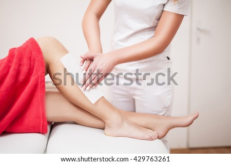 Beautician waxing woman a leg at salon / Depilation. Royalty-Free Stock Photo #429763261