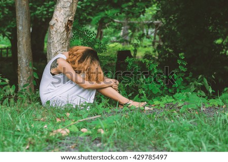 young hipster woman, sad, long-haired  sitting hugging legs.