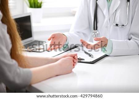 Close up of doctor and  patient  sitting at the desk near the window in hospital Royalty-Free Stock Photo #429794860
