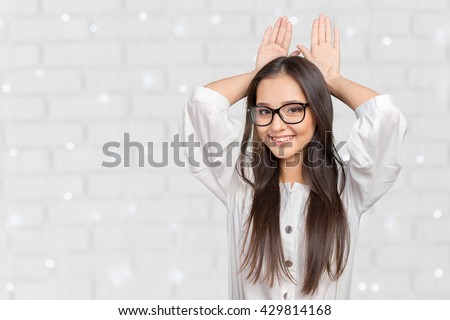 Happy woman showing rabbit ears with her palms