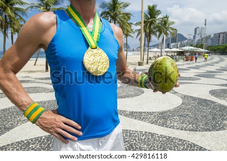 Gold medal athlete standing with green coconut coco gelado on the boardwalk at Copacabana Beach, Rio de Janeiro, Brazil