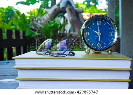 Glasses and alarm clock on the book