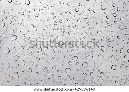 Raindrops on glasses surface. Natural Pattern of rain drops isolated on cloudy background. This picture is a bit blurry .