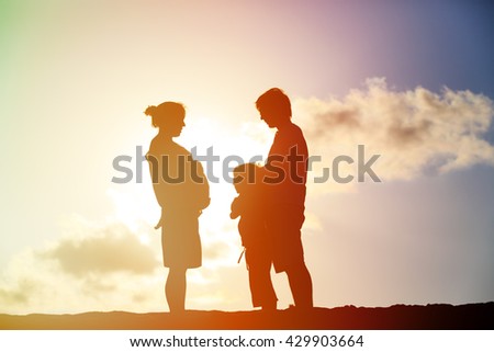 happy pregnant mother and father with son at sunset