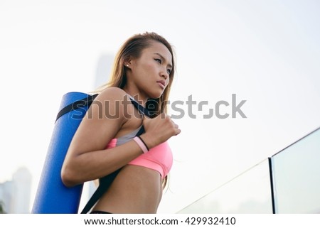 Young woman carrying yoga mat in city