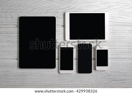Tablet computers and mobile phones on a white wooden background