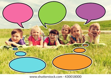 summer, childhood, leisure and people concept - group of happy kids lying on blanket or cover outdoors with colorful text bubble icons