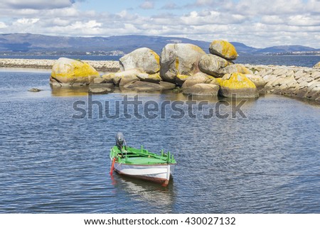 White fishing boat anchored on Vilaxoan harbor with granite bowling at background