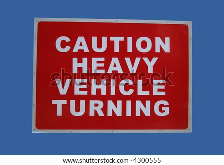 caution heavy vehicles turning sign on blue