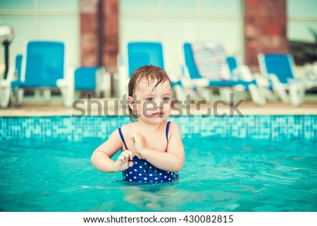 Happy child in swimming pool, beautiful girl swims