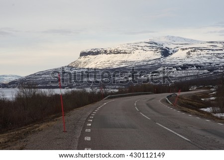 Landscape Picture of asphalt road in the Lapland in north Sweden Road from Kiruna to Narvik in Norway along big lake Tornetrask and mountains. Picture taken in spring, country still under snow and ice