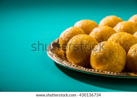 Bundi Laddoo or Motichoor Laddu prepared in pure ghee is a popular sweet item made during festivals (as offering) or weddings in India. Served in a brass plate over moody background. Selective focus