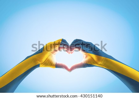 Sweden flag on people heart shape hands.