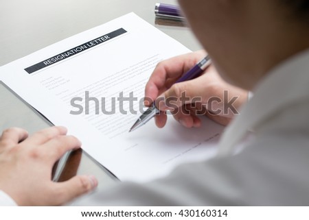 Business man signing his resignation letter on his desk before sending to his boss to quit his job.