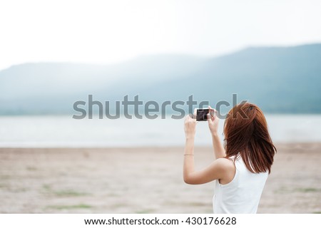 Young Asian woman taking photo with smart phone of landscape