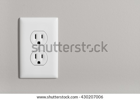 A white home electrical outlet on a light grey wall. Royalty-Free Stock Photo #430207006