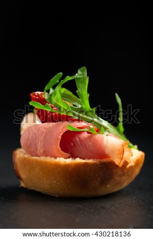 Sandwiches with duck breast and arugula on a black table