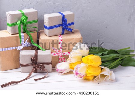 Yellow and white spring tulips and wrapped  boxes with presents. Selective focus. Place for text.
