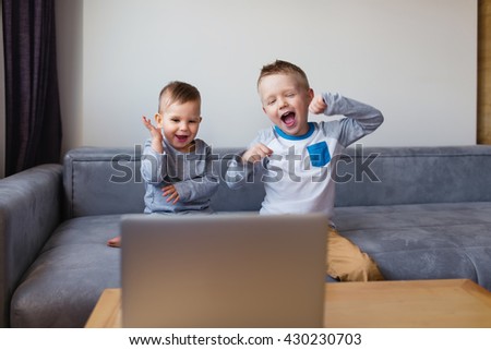 View of an excited boys  videocalling. Two cute siblings using laptop while sitting on sofa Royalty-Free Stock Photo #430230703