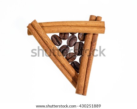 Roasted coffee beans in triangle of cinnamon sticks on white background