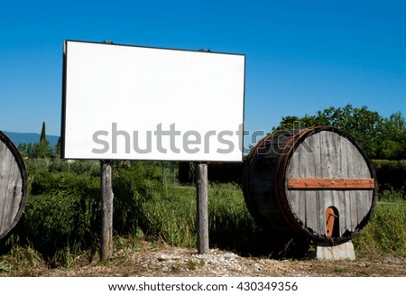 blank billboard in the countryside cultivated with traditional wooden barrel