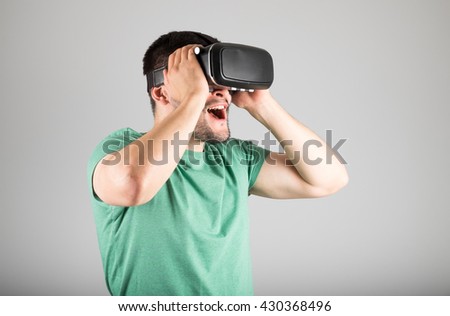 Handsome man wearing virtual reality glasses isolated on a gray background