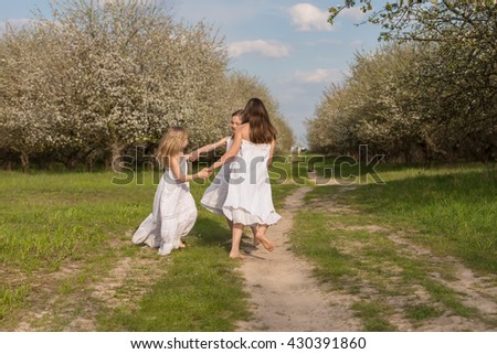 Three girls jump dance and whirl in the apple orchard