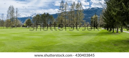 Beautiful panorama of golf resort with Alps mountains behind in Austria. Place for golf sport activity in summer with blue sky and clouds