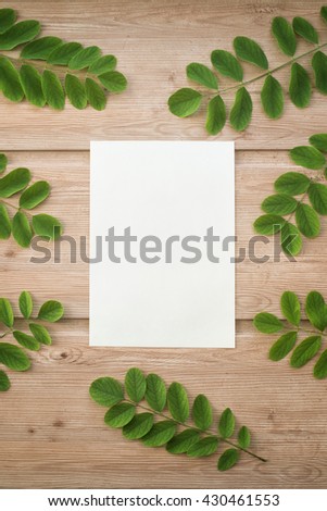 Border or banner of Green leaves on the wooden background and paper for notes. Top view. plant and leaf. organic template with space for text. watercolor paper. Ecology, nature