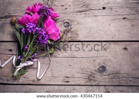 Pink peonies flowers on aged wooden background. Flat lay. Top view with copy space. Selective focus. Toned image.
