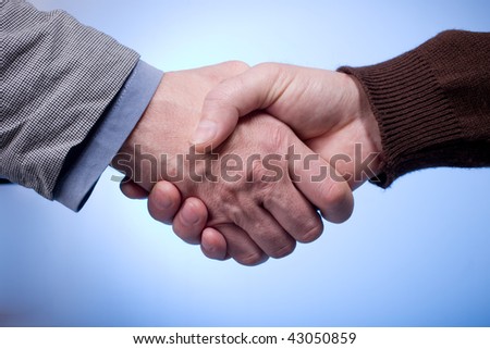 Close up of two man's hands shaking on blue background