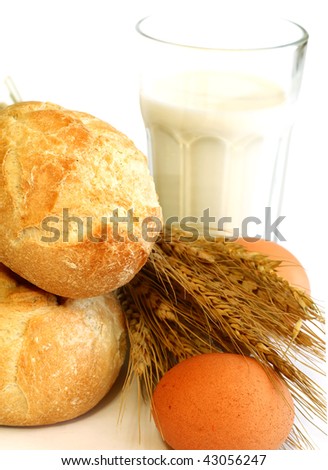 bread rolls, eggs and glass of milk on white