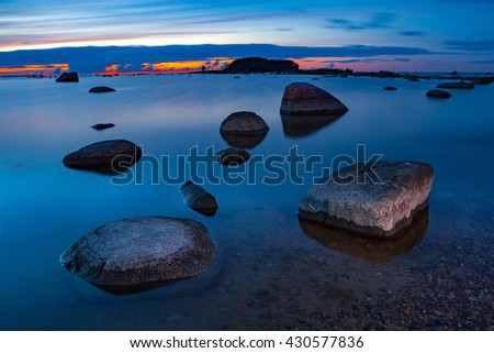 Beautiful view of late sunset over sea with stones on a long exposure and motion wave
