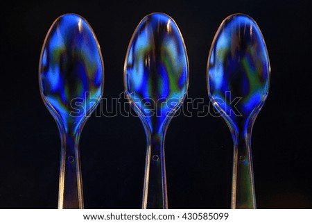 Blue and Green Polarized Spoons Isolated on a Black Background.