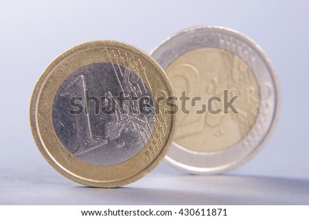 Standing coins one euro and two euro isolated on the gray background