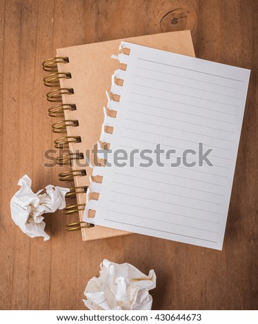 note book and crumpled on wooden background