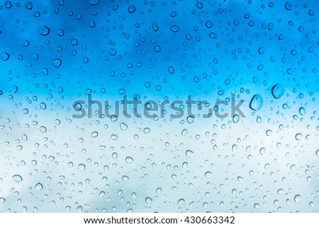 Drops of water on glass window over blue sky