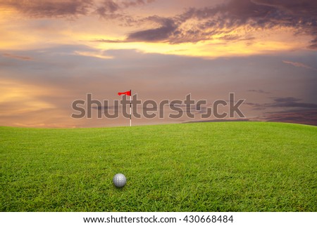 Golf ball on the lawn and blurred sky-clouds and sunlight