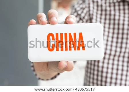 Man hand showing CHINA word phone with  blur business man wearing plaid shirt.