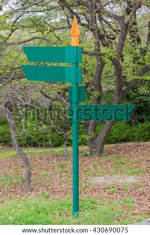 Blank direction green signpost standing in the park.