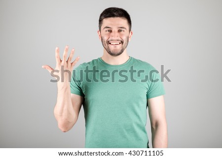 Handsome man counting to five isolated on a gray background