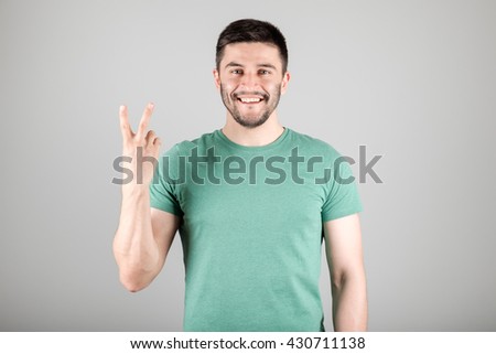 Handsome man counting to two isolated on a gray background
