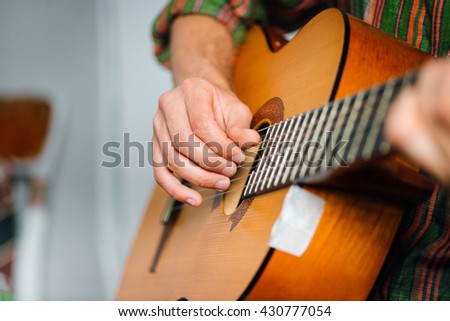 hipster man playing classical guitar, wears a hat and glasses, isolated on a gray background