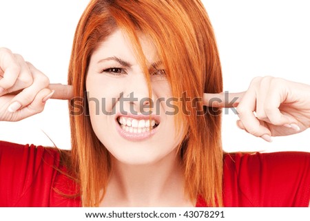 picture of unhappy redhead woman with fingers in ears