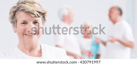 Panoramic picture of a smiling senior woman and her friends talking in the background